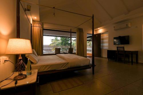 a bedroom with a bed and a desk and a window at Gubbi Goodu Green Resort in Bengaluru