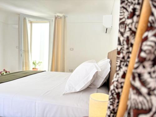 a bedroom with a bed with white sheets and a window at Lux Maris by Jdvacanze in Campomarino