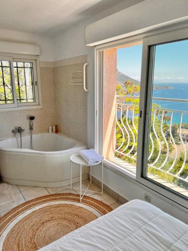 une salle de bain avec baignoire et une grande fenêtre dans l'établissement Bohème Beach Villa with seaview & private garden, Antheor, à Saint-Raphaël