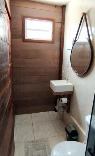 a bathroom with a sink and a mirror and a toilet at Chalé Madeira Nobres Asa Própria in Estivado
