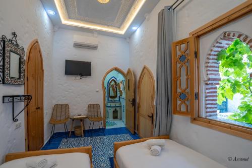 a room with a bed and a table and a window at Riad ALHAMBRA in Chefchaouene