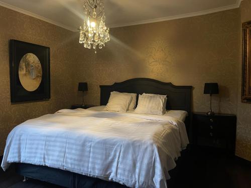 a bedroom with a bed with white sheets and a chandelier at Hotell Vaxblekaregården in Eksjö