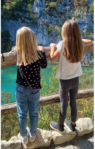 two little girls standing next to a fence at Family Resort Plitvice Lakes in Rastovača