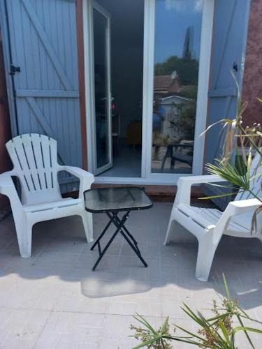 a porch with two white chairs and a table at Petit Lézard in Draguignan