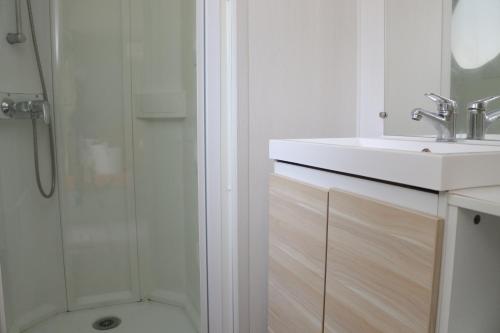 une salle de bain blanche avec un lavabo et une douche dans l'établissement Taluna, à Agde