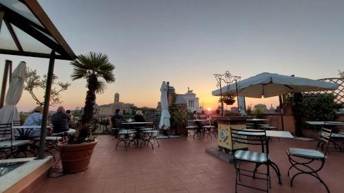 a rooftop patio with tables and chairs and a sunset at Residenza Maritti Decò Style- Guesthouse in Rome