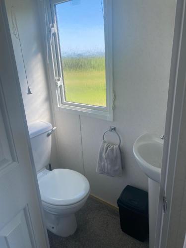 a bathroom with a toilet and a sink and a window at Coastal Chalet in Tudweiliog- Tyddyn Mawr in Pwllheli