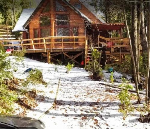 a log cabin in the woods with snow on the ground at Cabañas Alturas Chillan Katalina in Chillán