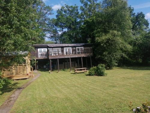 a large house with a deck in the yard at Loch Aweside Forest Cabins in Dalavich