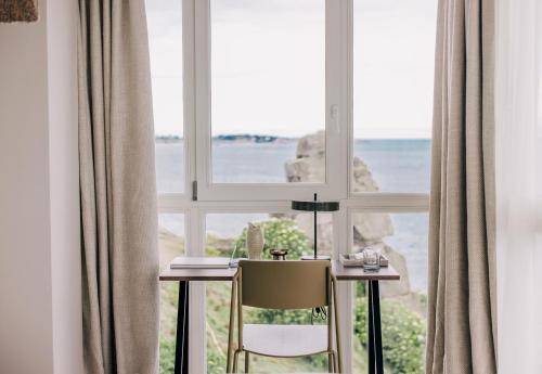 a table and a chair in front of a window at Les Bassans in Perros-Guirec