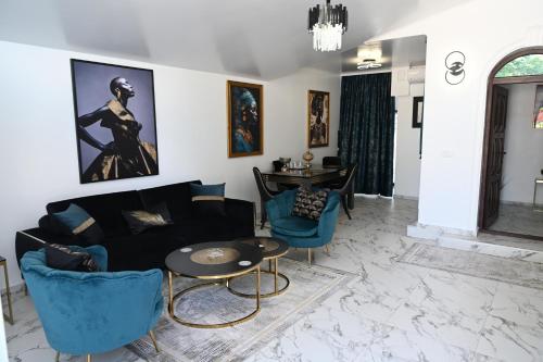 a living room with a black couch and blue chairs at Luxury Home in Cîmpulung