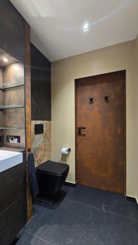 a bathroom with a toilet and a wooden door at Luxusowy Apartament MonteNegro in Nowęcin