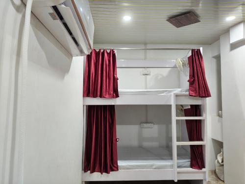 a small room with a bed with red curtains at D'Yogi Rooms & Dormitory in Varanasi