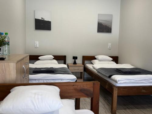 three beds in a room with white walls at Stacja Wilkołaz in Wilkołaz