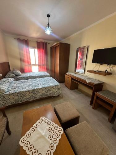a bedroom with a bed and a desk and a tv at شاليه بقرية اكوافيو in El Alamein