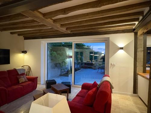 a living room with red couches and a sliding glass door at L'Ecrin des Marronniers in Abondant