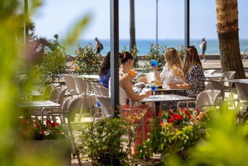 a group of people sitting at tables at the beach at Hotel Royalmar - Nouveau propriétaire in Cagnes-sur-Mer