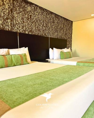 two beds sitting next to each other in a room at Hotel Colibrí Suites in Porlamar