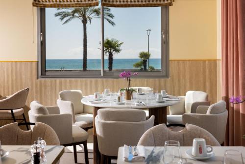 a dining room with tables and chairs and a large window at Hotel Royalmar - Nouveau propriétaire in Cagnes-sur-Mer