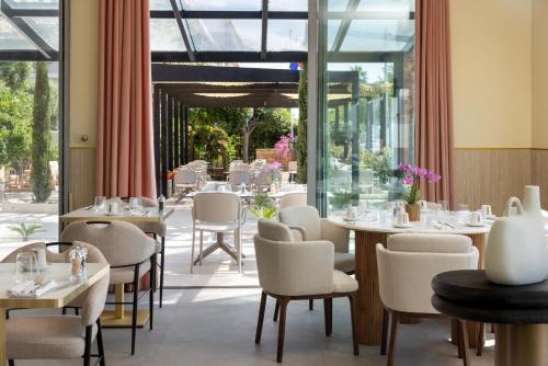 a restaurant with white tables and chairs and windows at Hotel Royalmar - Nouveau propriétaire in Cagnes-sur-Mer