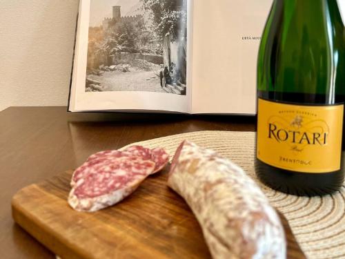 a piece of meat on a cutting board next to a bottle of wine at Appartamento al volt in Tenno
