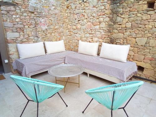 two chairs and a bench with a table and a stone wall at La Terrasse des Moulins Maison de Charme in Saint-Félix-Lauragais