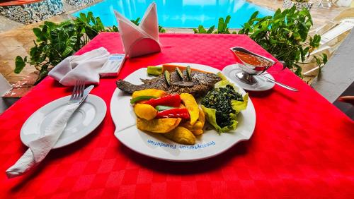 a plate of food with meat and vegetables on a red table at Milele Beach Hotel in Bamburi