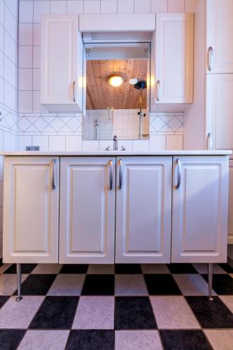 a kitchen with white cabinets and a checkered floor at Polden, house by Ramberg Beach in Ramberg