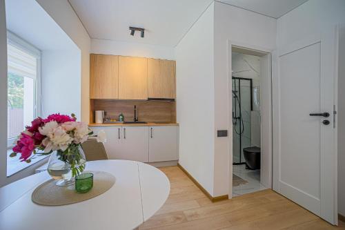 a kitchen with a white table and a vase of flowers at Green Apartment with free parking in Kaunas