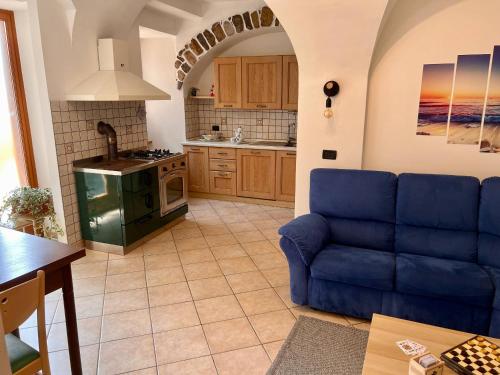 a living room with a blue couch in a kitchen at Appartamento al volt in Tenno