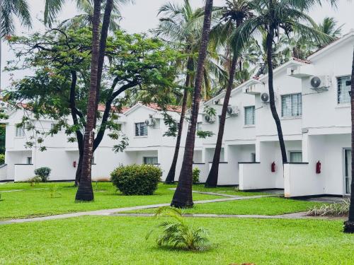 a row of palm trees in front of a white building at Milele Beach Hotel in Bamburi