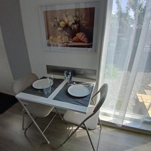a white table with two chairs and a table with two plates at Gäststuga i centrala Ystad #2 in Ystad