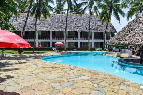 a resort with a swimming pool and a building at Milele Beach Hotel in Bamburi