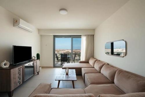 a living room with a couch and a television at Marassi Faya 3BR Retreat in El Alamein