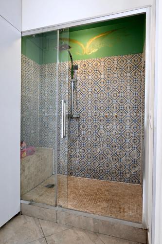 une douche avec une porte vitrée dans une salle de bain dans l'établissement Un jardin en Ville, à Nice