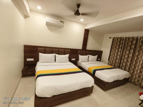 a hotel room with two beds and a window at Hotel Victoria City Mumbai in Mumbai