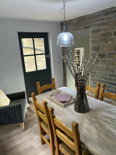 a dining room with a table with a vase on it at Heather Bank Cottage, Halifax. Yorkshire. HX2 7DD in Halifax