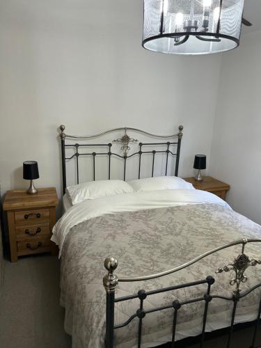 a bedroom with a bed and two night stands with lamps at Heather Bank Cottage, Halifax. Yorkshire. HX2 7DD in Halifax