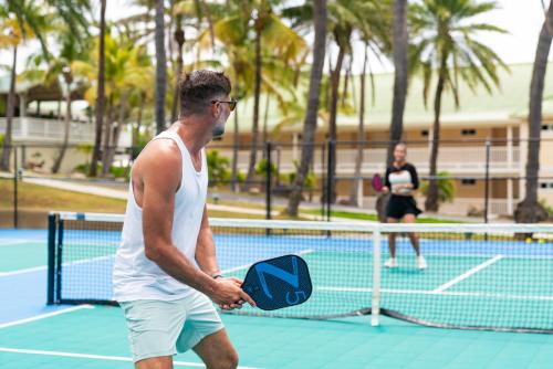 a man standing on a tennis court holding a racket at St. James's Club Resort - All Inclusive in English Harbour Town