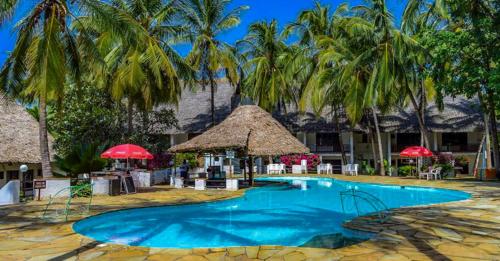 a swimming pool with palm trees and a resort at Milele Beach Hotel in Bamburi