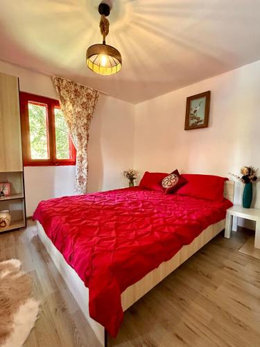 ein Schlafzimmer mit einem großen Bett mit roter Bettwäsche in der Unterkunft Căsuța Dede in Buzău