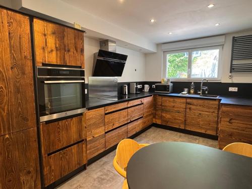 une cuisine avec des armoires en bois et une table à l'intérieur dans l'établissement Appartement dans une cité de caractère, à Mouthier-Haute-Pierre