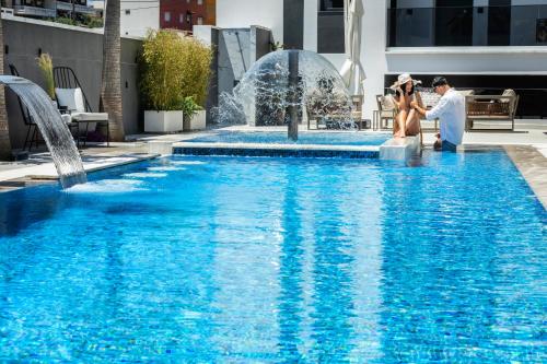 a bride and groom standing in front of a fountain at Bareti Boutique Estate in Kallithea Halkidikis