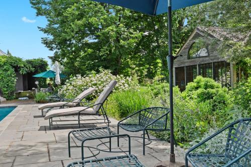 a row of chairs and an umbrella next to a pool at Stunning Cottage in Famous KY Garden -Sleeps 2 in Prospect