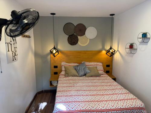 a bedroom with a bed and a fan on the wall at Hostal Pura Vida la 70 in Medellín