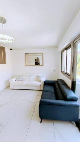 un salon avec un canapé bleu et une pièce blanche dans l'établissement Royal Lux Spacious seaside pool, à Nice
