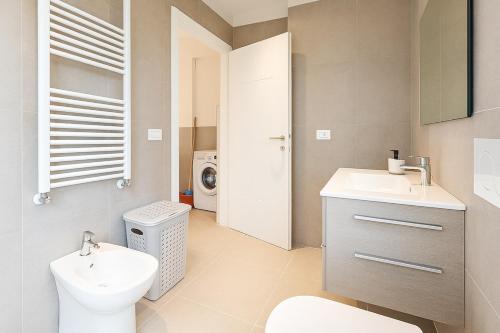 a bathroom with a toilet sink and a washing machine at Modern apartment with parking in Lignano Sabbiadoro