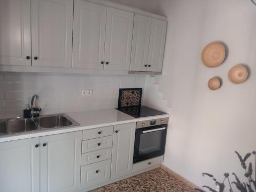 a kitchen with white cabinets and a sink at Elmar Mosaic Suites in Paralion astros