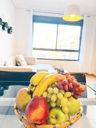 a basket of fruit on a table in a living room at Elegante apartamento con piscina A un paso de Sevilla San Miguel in Camas
