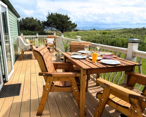 a wooden table and chairs on a deck at Sanderling, 289 Ynyslas Beach, Borth in Borth
